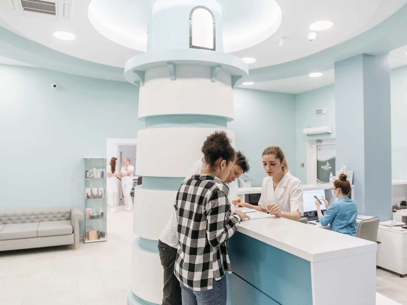 A bright, well-branded clinic reception desk with staff helping patients